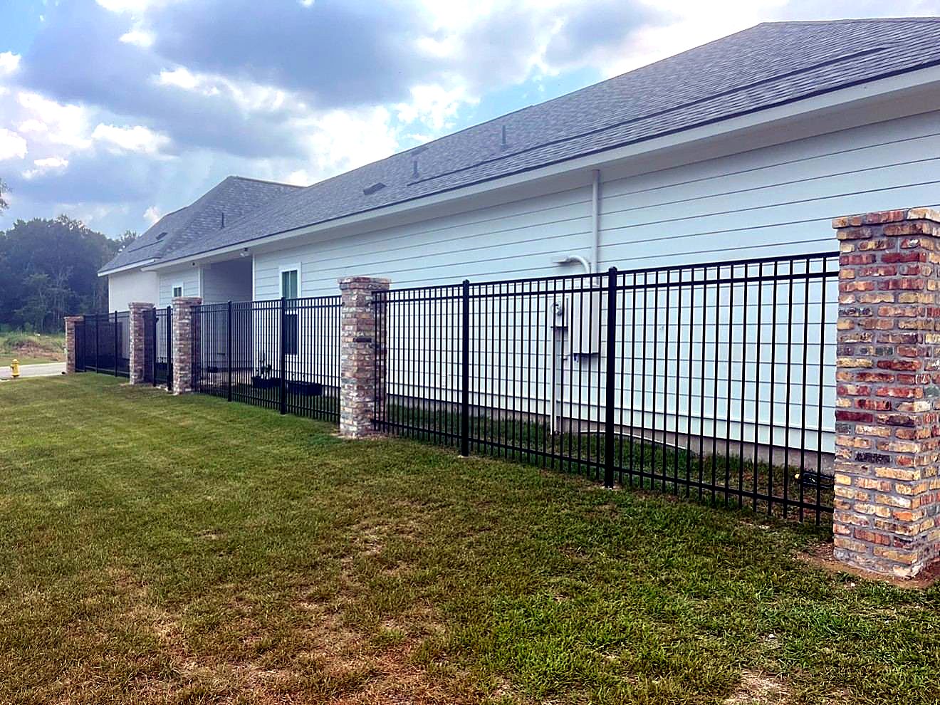 Black aluminum panel fence with brick columns