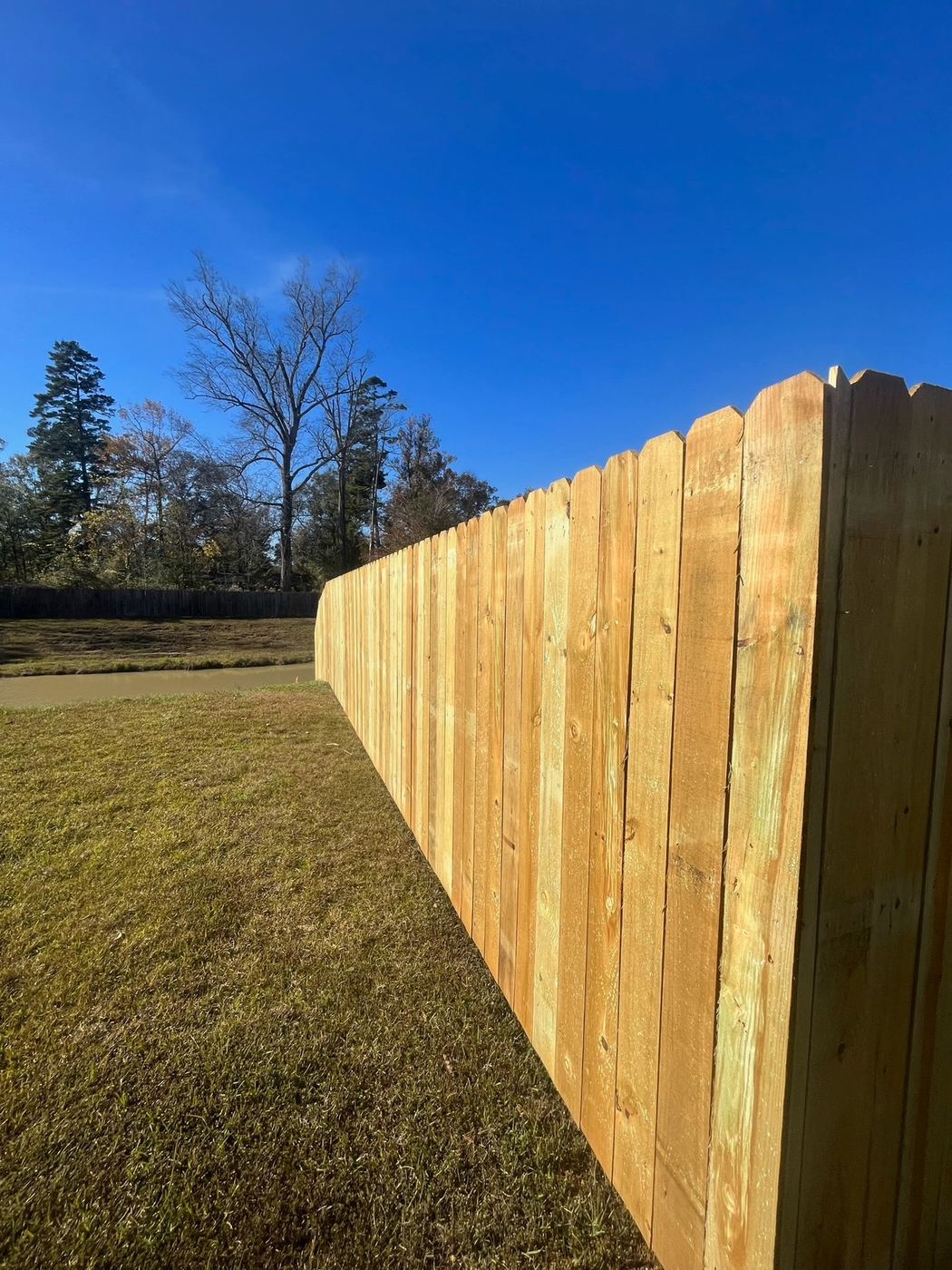 Wood dog ear fence along a pond